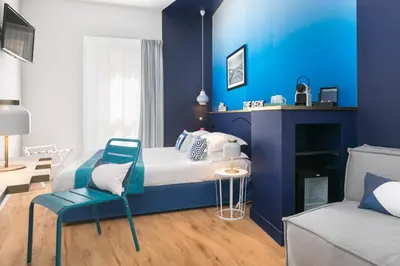 a bedroom with blue walls and a bed and a chair at The Deck Hotel by Happyculture in Nice