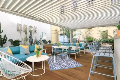 a room with a couch and tables and chairs at The Deck Hotel by Happyculture in Nice