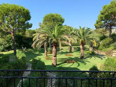 a view from a balcony of a park with palm trees at Appartement agréable en bord de mer in Villefranche-sur-Mer