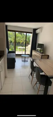 a living room with a table and a laptop on a desk at Appartement agréable en bord de mer in Villefranche-sur-Mer