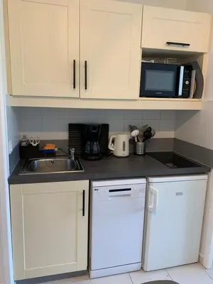 a kitchen with white cabinets and a sink and a microwave at Appartement agréable en bord de mer in Villefranche-sur-Mer