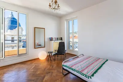 a bedroom with a bed and a chair and windows at Ambassador Palace AP2095 by Riviera Holiday Homes in Nice