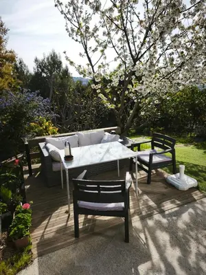 a patio with a table and chairs and a tree at Rez de villa avec beau jardin et belle vue in Saint-Laurent-du-Var