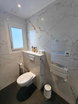 a white bathroom with a toilet and a window at Rez de villa avec beau jardin et belle vue in Saint-Laurent-du-Var