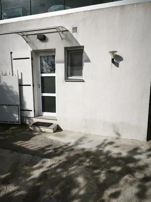 a white building with a door and a window at Rez de villa avec beau jardin et belle vue in Saint-Laurent-du-Var
