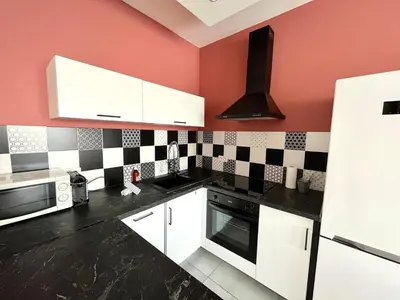 a kitchen with white cabinets and a red wall at 2 Bedrooms - Sea View Apartment in Nice