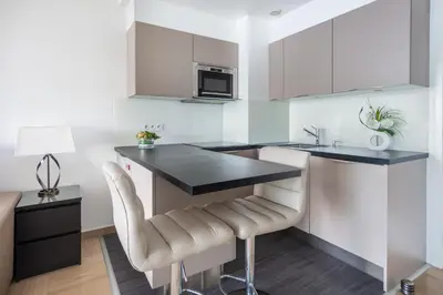 a kitchen with a black counter top and white cabinets at SEA FRONT - panoramic sea view studio with terrace in Nice
