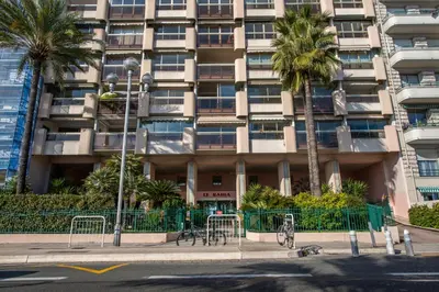 a tall building with palm trees in front of it at SEA FRONT - panoramic sea view studio with terrace in Nice