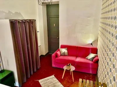 a red couch in a living room with a curtain at GARE 5 minutes GARIBALDI RÉPUBLIQUE chambre PRIVEE non FUMEUR pour voyageurs CALMES TRAM au pied de l'immeuble in Nice