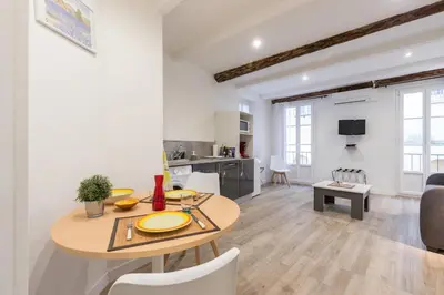 a dining room and living room with a table and chairs at Cosy Studio in the Old Town - St François Square in Nice