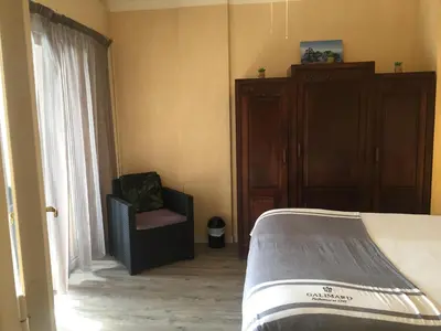 a bedroom with a bed and a chair next to a window at Charmant appartement bord de mer, Plage in Cagnes-sur-Mer