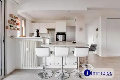 a kitchen with white cabinets and white bar stools at Air-conditioned apartment in the Libération district in Nice