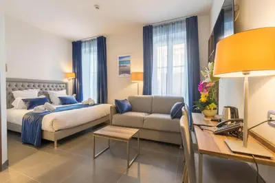 a hotel room with a bed and a couch at Hôtel Nice Azur Riviera in Nice