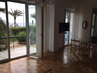 a living room with sliding glass doors and a table and a television at 91 Promenade des Anglais le stellamar in Nice