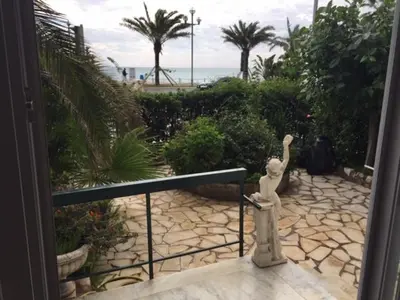 a statue of a woman standing on a walkway near the beach at 91 Promenade des Anglais le stellamar in Nice