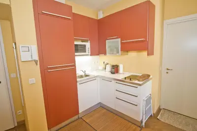 a small kitchen with red cabinets and a sink at PROMENADE HOLIDAY - GRIMALDI CITY CENTER in Nice