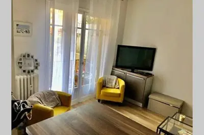 a living room with a tv and a yellow chair at Appartement NICE proche MER et CENTRE in Nice