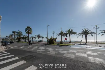 a street with a crosswalk with palm trees and the beach at Suite Versailles Five Stars Holiday House in Nice