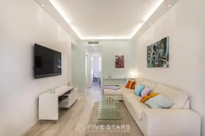 a white living room with a couch and a tv at Suite Versailles Five Stars Holiday House in Nice