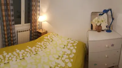 a bedroom with a bed with a yellow blanket with flowers at Cosy Room in the centre in Saint-Laurent-du-Var