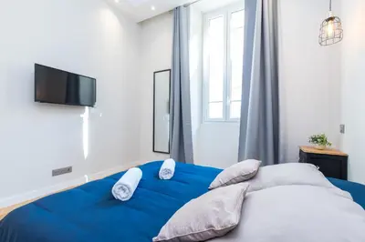 a bedroom with a blue bed with pillows and a tv at Brand New 1 Bdr Place du Pin in Nice