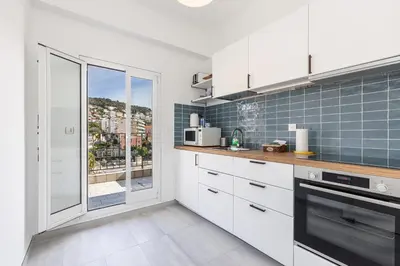 a kitchen with white cabinets and a large window at Extraordinary View on Port and Castle Hill - 1 Bdr & Parking in Nice