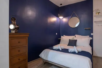 a bedroom with a blue wall and a bed with towels at Papa Riviera - Nice old town - 1-3 pers in Nice