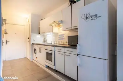 a kitchen with white cabinets and a refrigerator at Studio Jardin Fleuris Parking in Nice