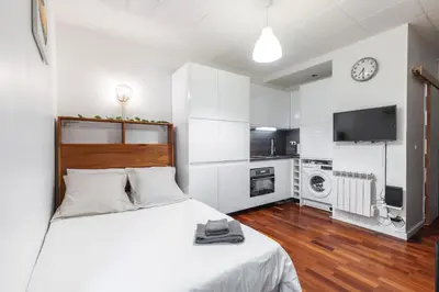 a white bedroom with a bed and a kitchen at Studio en plein cœur de la vieille ville à Nice in Nice