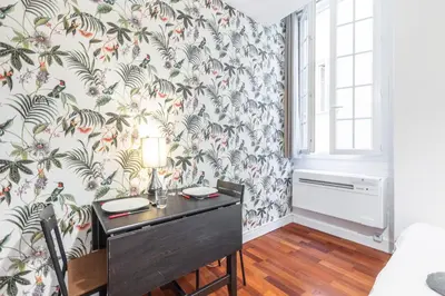 a room with a desk and a wall with floral wallpaper at Studio en plein cœur de la vieille ville à Nice in Nice