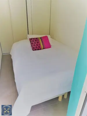 a small bedroom with a white bed with a pink pillow at NICE VIEW Jolie Studio avec Jardin in Nice