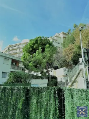 a tree behind a fence in front of a building at NICE VIEW Jolie Studio avec Jardin in Nice