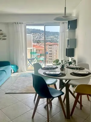 a dining room with a table and chairs and a large window at Risso - charming one bedroom with a balcony in Nice