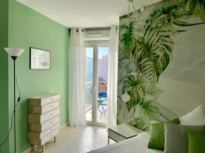 a bedroom with a green wall with a mural of palm trees at Risso - charming one bedroom with a balcony in Nice