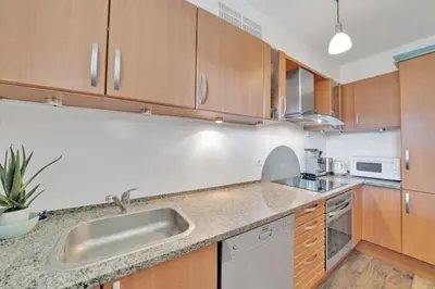 a kitchen with wooden cabinets and a sink at La Prom - a two bedroom apartment with a sea view in Nice