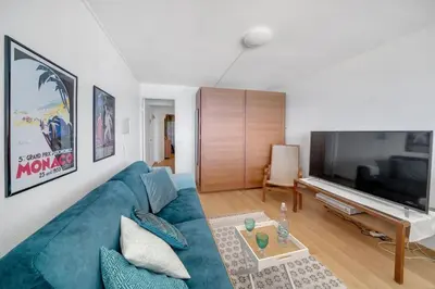 a living room with a blue couch and a large television at La Prom - a two bedroom apartment with a sea view in Nice