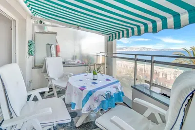 a balcony with a table and chairs and the ocean at La Prom - a two bedroom apartment with a sea view in Nice