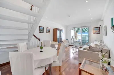a white living room with a white table and chairs at La Prom - a two bedroom apartment with a sea view in Nice