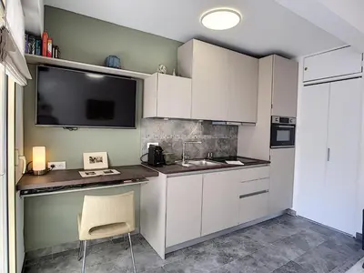 a kitchen with white cabinets and a sink and a tv at Nestor&Jeeves - BERLIOZ SUITE - Downtown - Close beaches in Nice