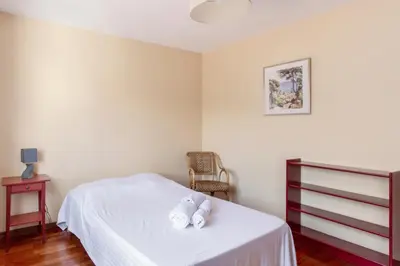 a bedroom with a bed with white sheets and a chair at Le Refuge Acajou - Welkeys in Nice