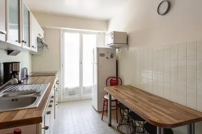 a kitchen with a wooden table and a refrigerator at Le Refuge Acajou - Welkeys in Nice