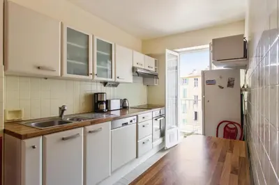 a kitchen with white cabinets and a sink and a refrigerator at Le Refuge Acajou - Welkeys in Nice