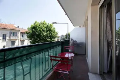a balcony with two red chairs and a table on it at Studio à Nice ensoleillé proche centre et plage in Nice