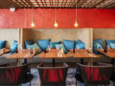 a row of tables in a restaurant with blue pillows at Crowne Plaza - Nice - Grand Arenas by IHG in Nice