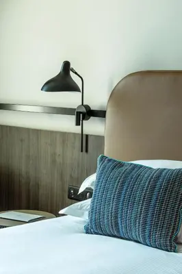a bed with a blue pillow and a lamp at Crowne Plaza - Nice - Grand Arenas by IHG in Nice