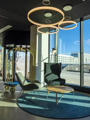 a lobby with two chairs and a table and a chandelier at Holiday Inn Express - Nice - Grand Arenas by IHG in Nice