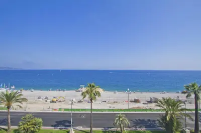a view of a beach with palm trees and the ocean at BEACHSIDE SUITE PANORAMIC - PROMENADE HOLIDAY in Nice