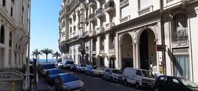 a street with cars parked next to buildings and the ocean at Large beautiful studio near the NEGRESCO HOTEL in Nice