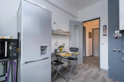 a small kitchen with a table and a refrigerator at Beau 3 pièces, 7 pers, 2 terrasses, centre, calme, sécurité in Nice