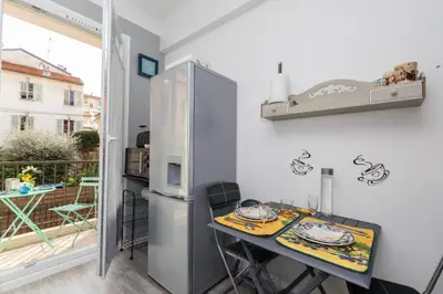 a small kitchen with a table and a refrigerator at Beau 3 pièces, 7 pers, 2 terrasses, centre, calme, sécurité in Nice